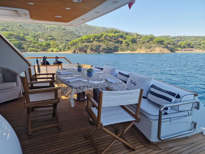 Toi Moi Et Roby Yacht Photos Pics Luxurious Diano 29 yacht deck with dining setup, overlooking serene coastal scenery.