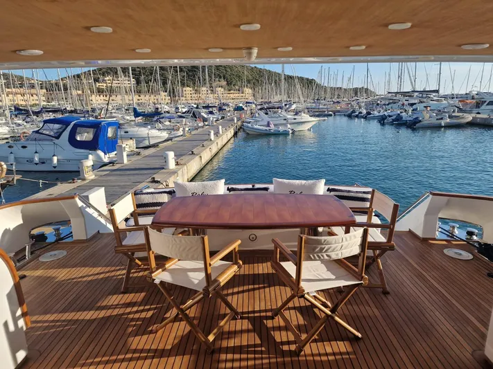 Toi Moi Et Roby Yacht Photos Pics Luxury yacht deck with wooden chairs and table, overlooking marina with boats. Diano 29, 2008 model.