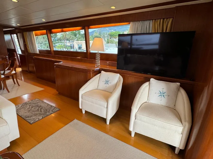 Toi Moi Et Roby Yacht Photos Pics Luxurious yacht interior with modern decor, featuring two armchairs, a large TV, and elegant wood paneling.