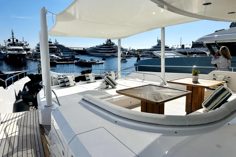 Optimism Yacht Photos Pics Luxurious 2023 Majesty 120 yacht deck with elegant seating, overlooking marina filled with yachts.