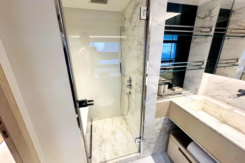 Optimism Yacht Photos Pics Luxurious marble bathroom in 2023 Majesty 120 yacht, featuring glass shower and modern fixtures.