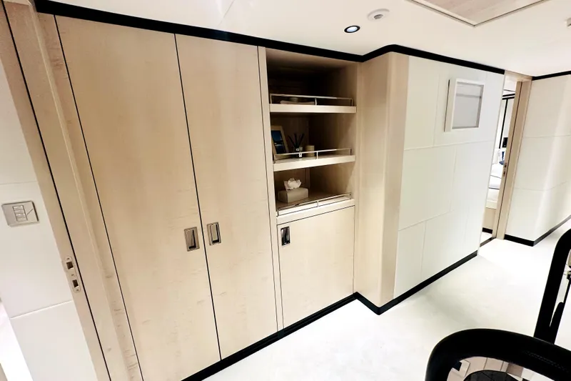 Optimism Yacht Photos Pics Modern interior of 2023 Majesty 120 yacht with sleek wooden cabinetry and open shelving.