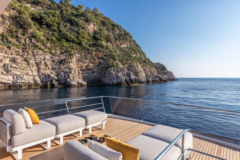 Absolute Navetta 64 Yacht Photos Pics Luxury yacht Absolute Navetta 64 deck with ocean view, 2025 model, near rocky coastline.
