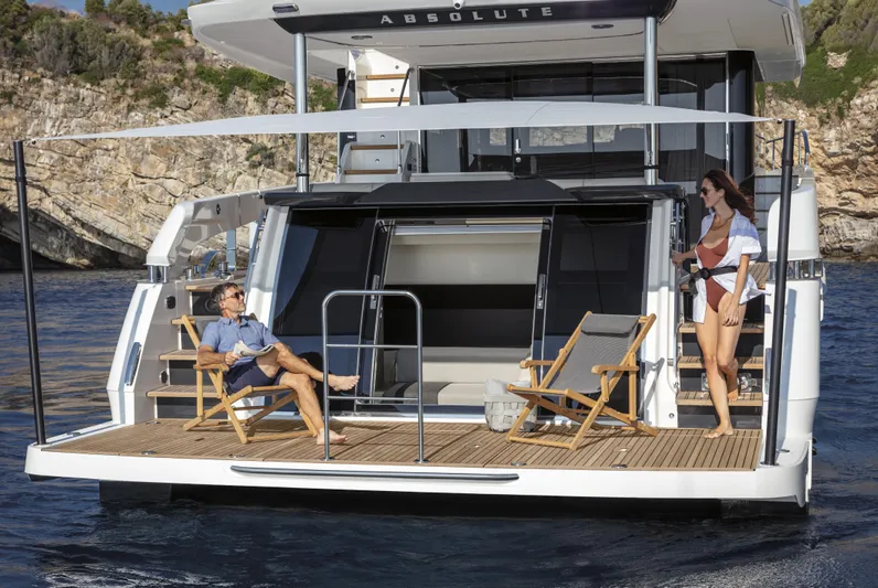 Absolute Navetta 64 Yacht Photos Pics 2025 Absolute Navetta 64 yacht with people relaxing on the deck, scenic coastal backdrop.