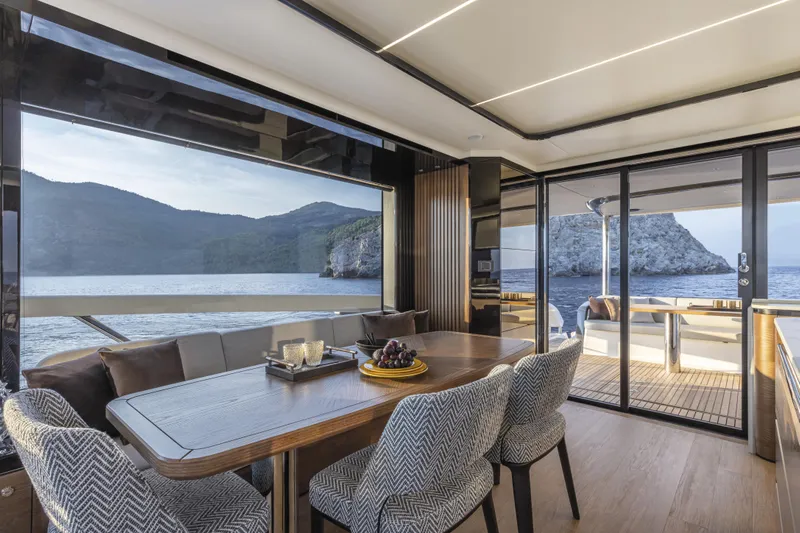 Absolute Navetta 64 Yacht Photos Pics Luxurious interior of 2025 Absolute Navetta 64 yacht with ocean view and elegant dining area.