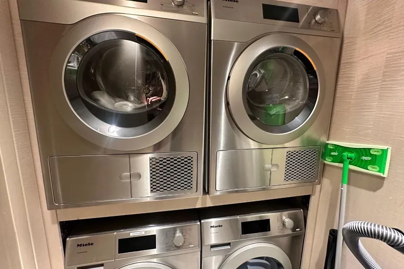 Optimism Yacht Photos Pics Stacked Miele laundry machines in a compact space, featuring a 2024 Majesty 120 model.