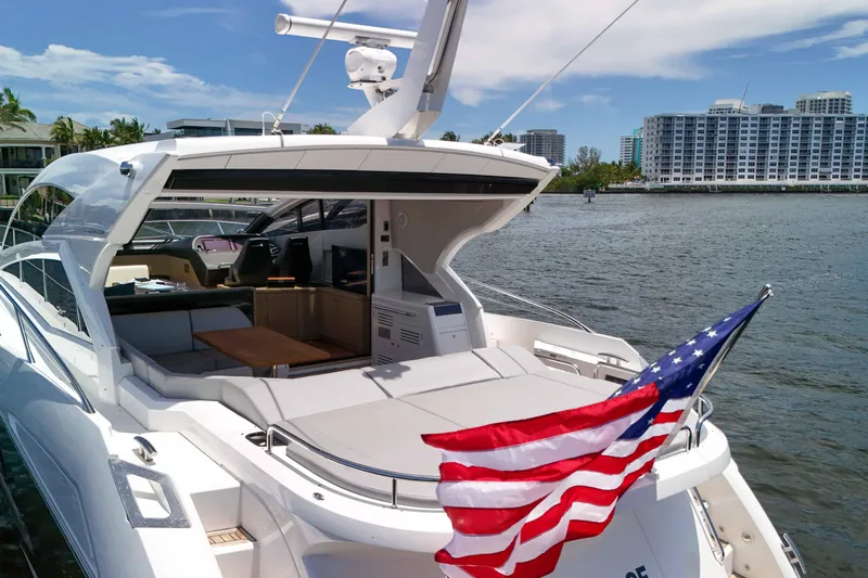  Yacht Photos Pics 2017 Sunseeker Predator 57 yacht with American flag, docked near waterfront buildings.