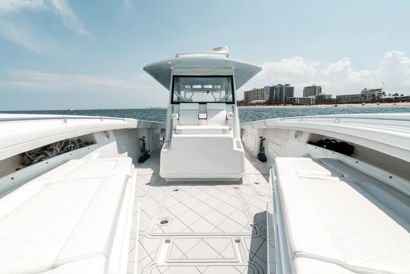  Yacht Photos Pics 2017 Yellowfin 42 boat with spacious deck, cruising near a coastal cityscape.