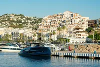 2024 Solaris Power 60 Open yacht docked in a scenic marina with hillside buildings.
