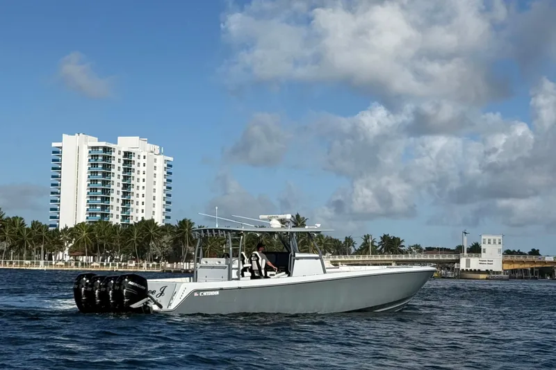  Yacht Photos Pics 2023 Contender 44 CB boat cruising near a coastal cityscape with palm trees.