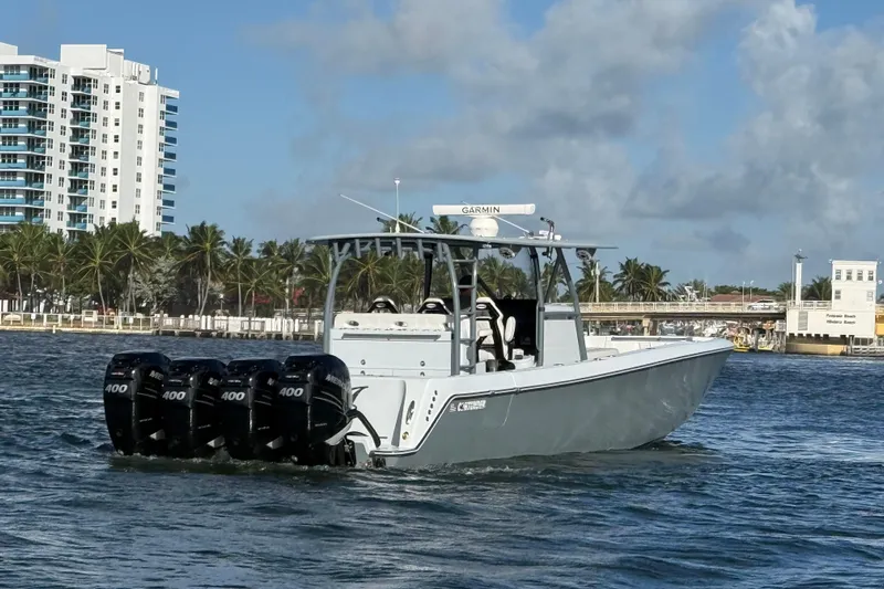  Yacht Photos Pics 2023 Contender 44 CB boat with four engines cruising near a coastal cityscape.