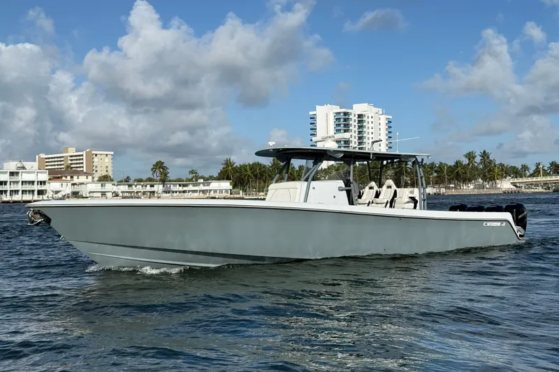  Yacht Photos Pics 2023 Contender 44 CB boat cruising near coastal buildings and palm trees.