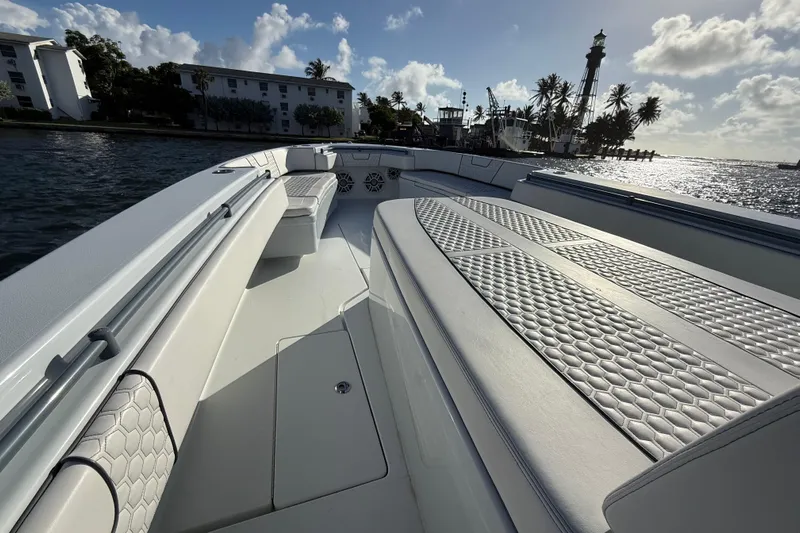  Yacht Photos Pics 2023 Contender 44 CB boat interior with cushioned seating, ocean view, and lighthouse in background.
