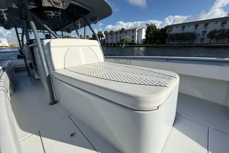  Yacht Photos Pics 2023 Contender 44 CB boat with cushioned seating, docked by waterfront buildings.