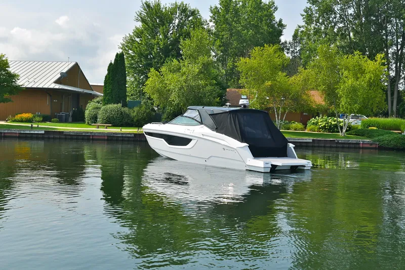  Yacht Photos Pics 2026 Cruisers Yachts 38 GLS I/O in a serene lakeside setting with lush greenery.