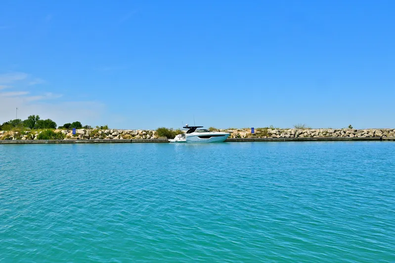  Yacht Photos Pics 2026 Cruisers Yachts 38 GLS I/O on calm blue water near rocky shoreline.