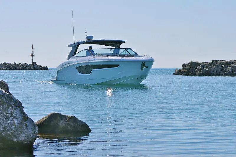  Yacht Photos Pics 2026 Cruisers Yachts 38 GLS I/O navigating calm waters near rocky shoreline.
