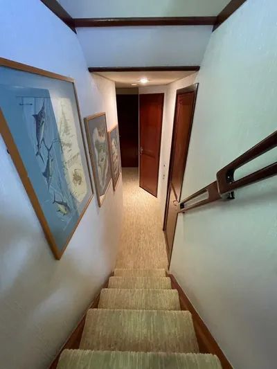 Moonshine Yacht Photos Pics Stairway inside 1985 Hatteras Enclosed Bridge yacht with framed artwork on walls.