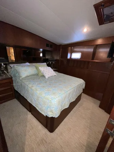 Moonshine Yacht Photos Pics 1985 Hatteras Enclosed Bridge bedroom with wood paneling and cozy bedding.