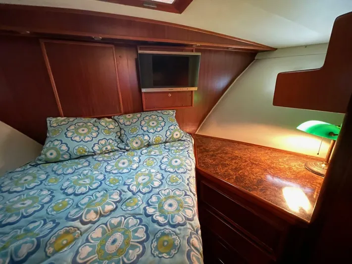Moonshine Yacht Photos Pics 1985 Hatteras Enclosed Bridge cabin with floral bedding, wood paneling, and a small TV.