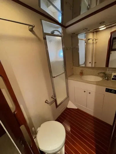 Moonshine Yacht Photos Pics 1985 Hatteras Enclosed Bridge yacht bathroom with shower, sink, and wooden flooring.