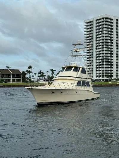 Moonshine Yacht Photos Pics 1985 Hatteras Enclosed Bridge yacht cruising near waterfront buildings under cloudy skies.