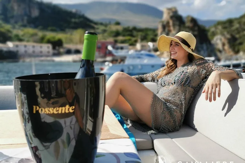  Yacht Photos Pics Woman relaxing on a Dufour 56 Exclusive yacht with wine, scenic coastal backdrop.