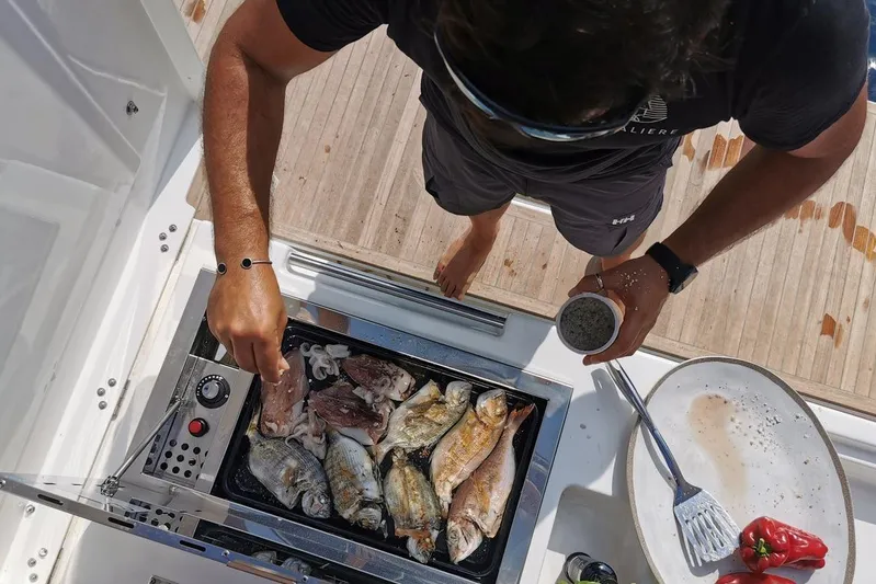  Yacht Photos Pics Man grilling fish on a Dufour 56 Exclusive yacht, 2020 model.