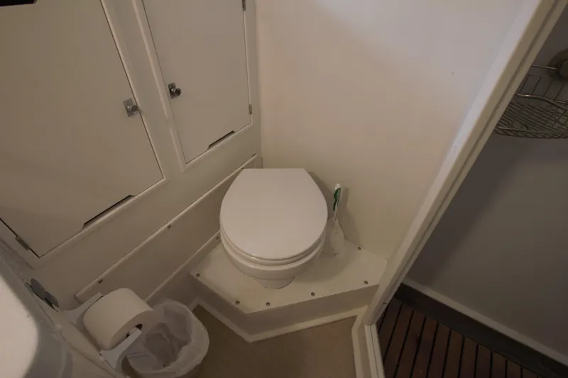  Yacht Photos Pics 1963 Huckins Linwood yacht bathroom with toilet, storage cabinets, and wooden flooring.