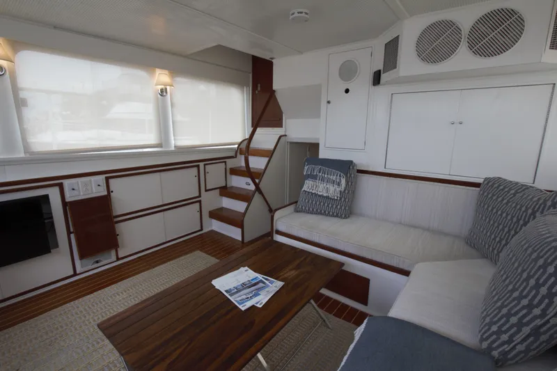  Yacht Photos Pics 1963 Huckins Linwood yacht interior with cozy seating, wooden table, and elegant decor.