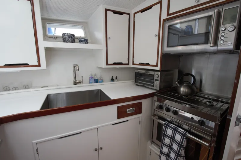  Yacht Photos Pics 1963 Huckins Linwood yacht kitchen with stainless steel appliances and white cabinetry.