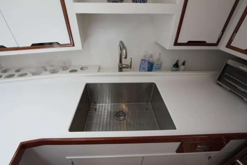  Yacht Photos Pics 1963 Huckins Linwood yacht kitchen with stainless steel sink and white cabinetry.