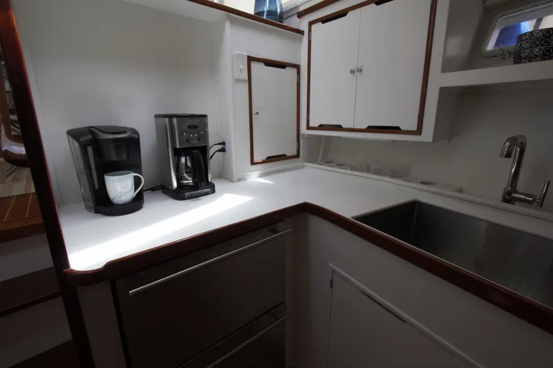  Yacht Photos Pics 1963 Huckins Linwood yacht kitchen with coffee makers, sink, and white cabinetry.