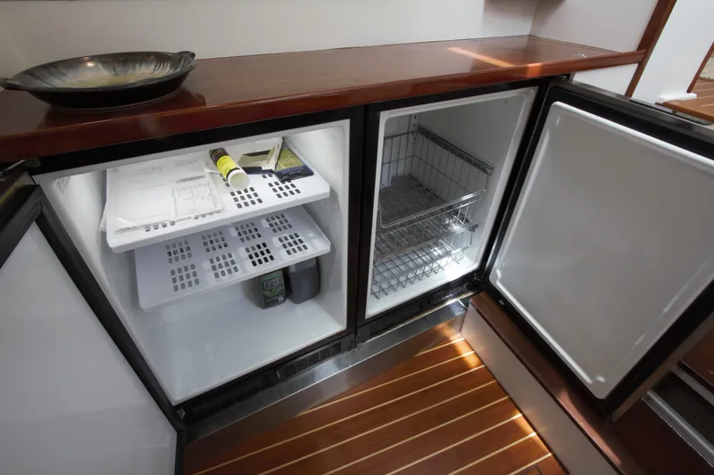  Yacht Photos Pics Open refrigerator on 1963 Huckins Linwood yacht, showcasing interior shelves and wooden flooring.