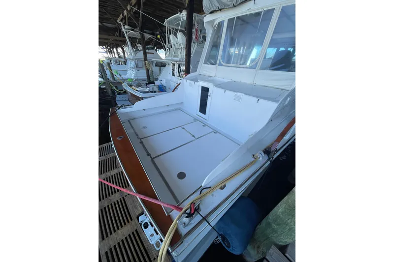  Yacht Photos Pics 1963 Huckins Linwood boat deck in a covered marina, showcasing spacious layout and classic design.