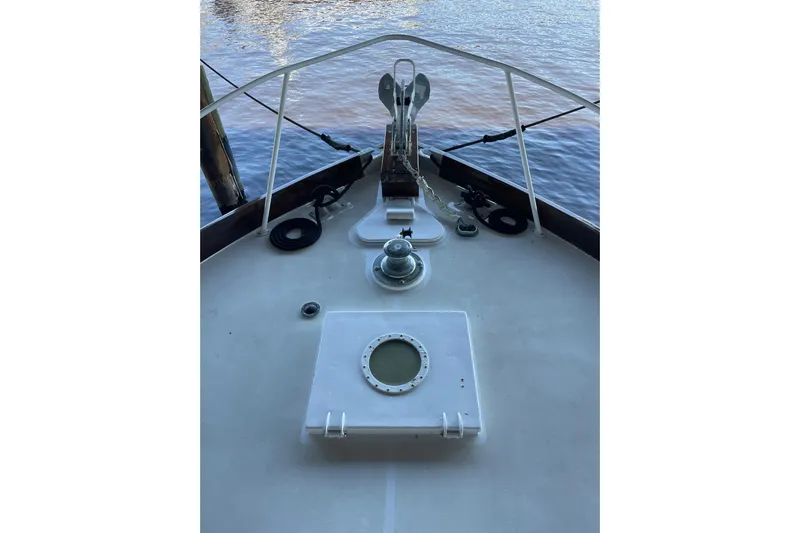  Yacht Photos Pics Bow of 1963 Huckins Linwood boat with anchor and winch, docked by calm water.