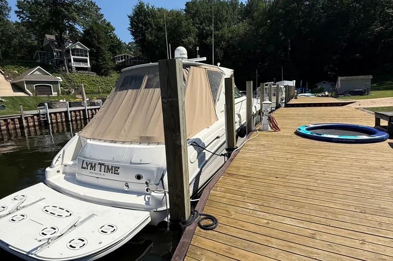  Yacht Photos Pics 1998 Sea Ray 540 Sundancer docked at a wooden pier, surrounded by lush greenery.