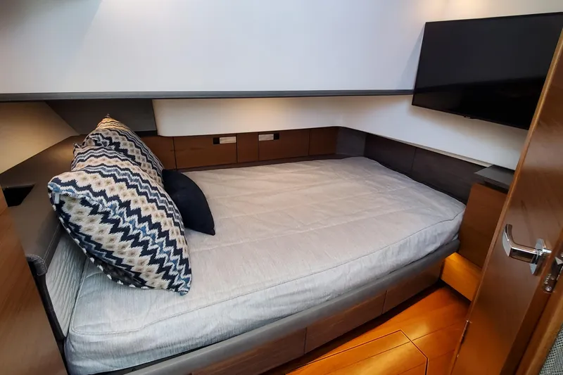 Pouge Life Yacht Photos Pics 2021 Tiara Sport 38 LS cabin with bed, pillows, and wall-mounted TV.