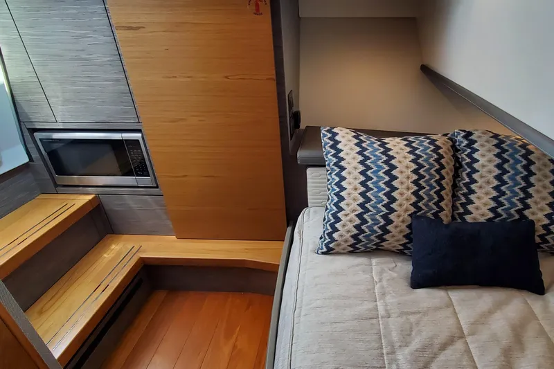 Pouge Life Yacht Photos Pics 2021 Tiara Sport 38 LS interior with bed, patterned pillows, and built-in microwave.