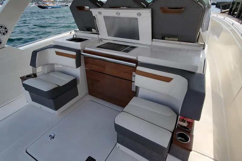 Pouge Life Yacht Photos Pics 2021 Tiara Sport 38 LS boat interior with seating and kitchenette, docked by the water.