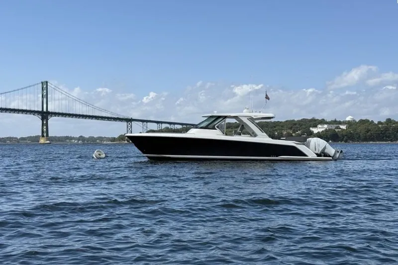 Pouge Life Yacht Photos Pics 2021 Tiara Sport 38 LS boat on water near bridge, clear sky background.