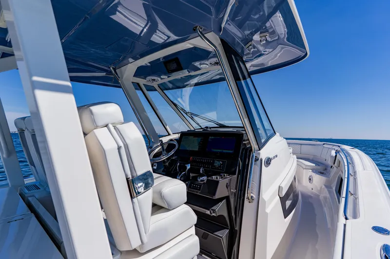 Blue Skies Yacht Photos Pics 2022 Pursuit S 378 Sport boat interior with helm, ocean view, and blue sky.
