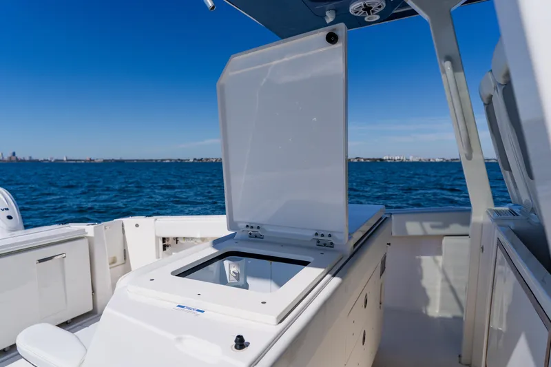 Blue Skies Yacht Photos Pics 2022 Pursuit S 378 Sport boat interior with open storage compartment, ocean view.