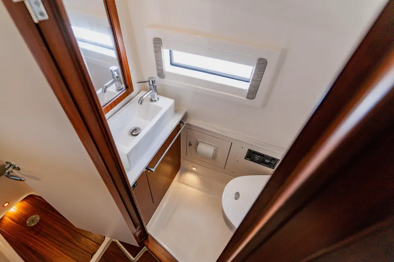 Blue Skies Yacht Photos Pics 2022 Pursuit S 378 Sport boat bathroom with sink, toilet, and window.