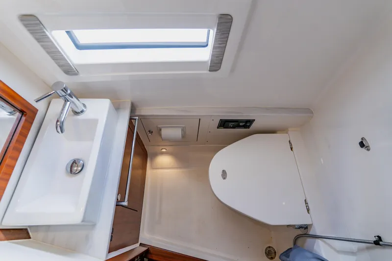 Blue Skies Yacht Photos Pics 2022 Pursuit S 378 Sport boat bathroom with sink, toilet, and window.