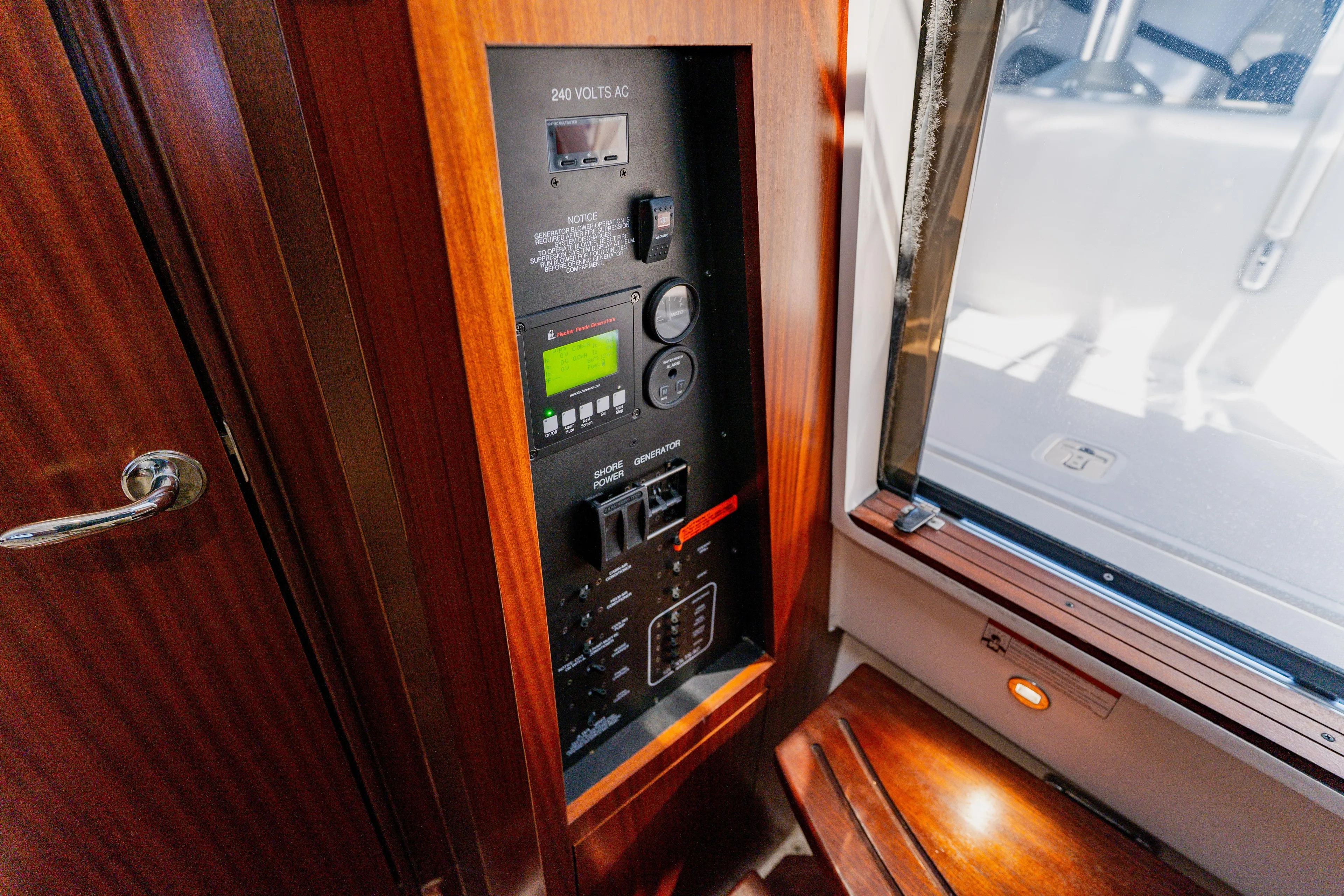 Blue Skies Yacht Photos Pics 2022 Pursuit S 378 Sport electrical panel with wooden finish and window view.