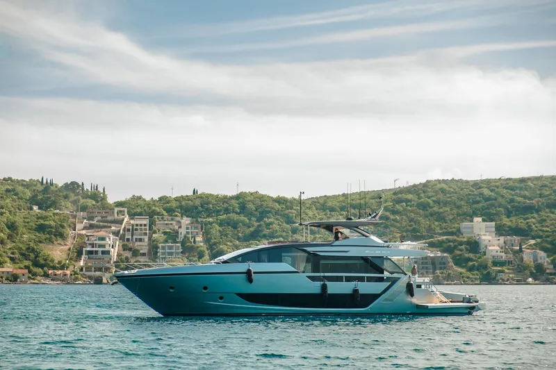  Yacht Photos Pics Luxury 2022 Riva 82' Diva yacht cruising near scenic coastal landscape.