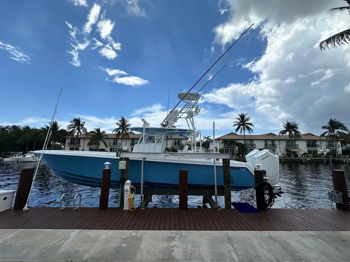  Yacht Photos Pics 2024 Contender 39 ST boat docked by waterfront homes under a partly cloudy sky.