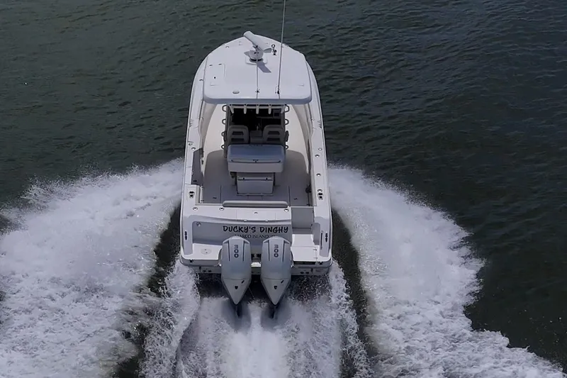 Ducky's Dinghy Yacht Photos Pics 2020 Boston Whaler 330 Outrage cruising on water, rear view with twin engines.