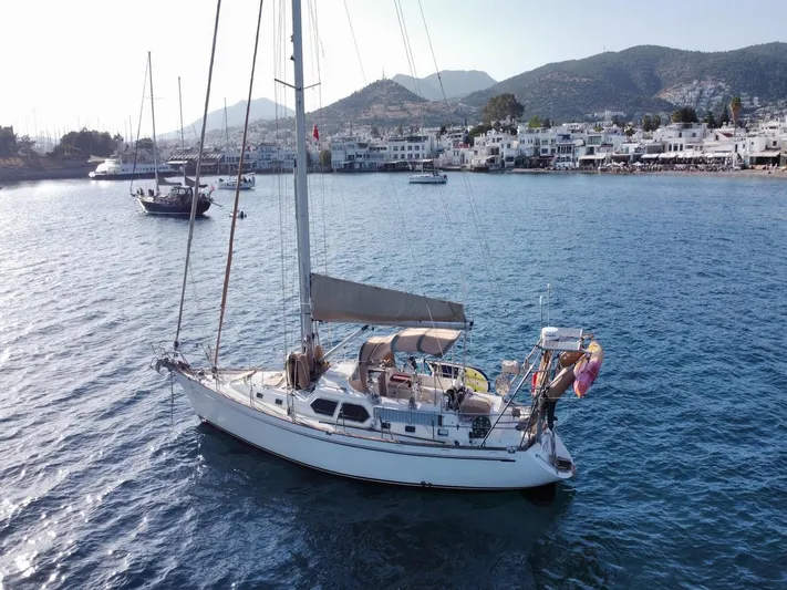 Tutkum Yacht Photos Pics Sailboat Tayana 48 (2007) anchored in scenic coastal waters with mountains and buildings in the background.